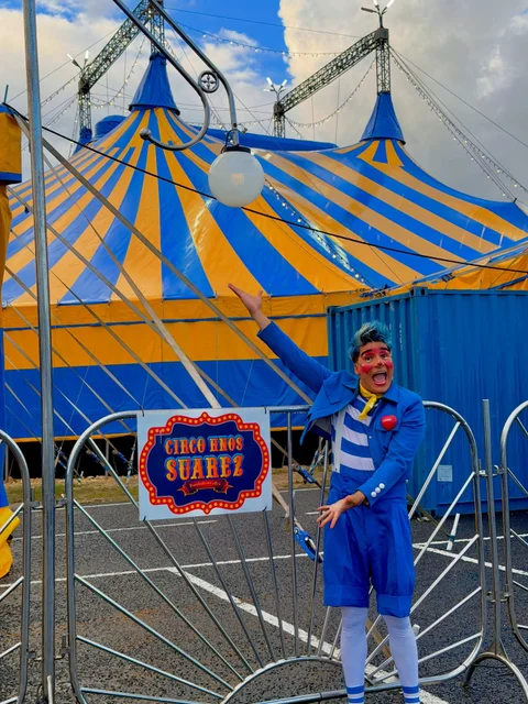Artista con traje azul dando la bienvenida delante de la carpa.