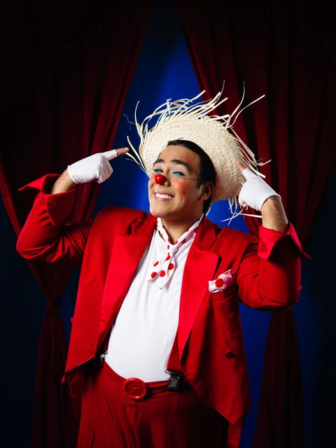 Payaso con traje rojo y sombrero de paja, sonriendo.